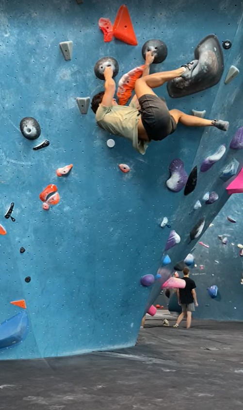 David working through an overhanging indoor bouldering route.